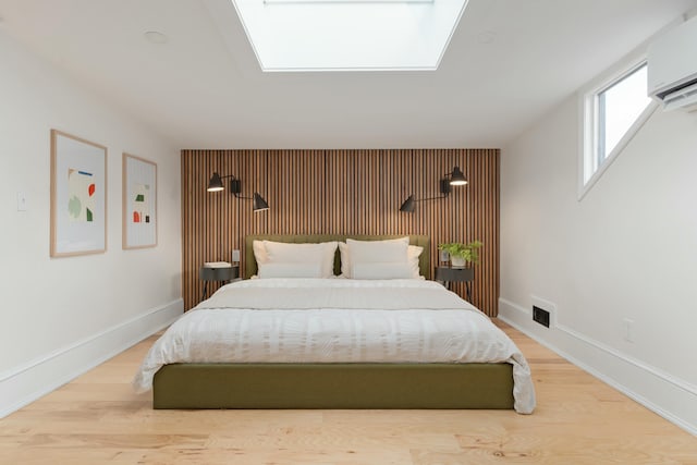 bedroom featuring wood finished floors, visible vents, baseboards, electric panel, and a wall mounted air conditioner