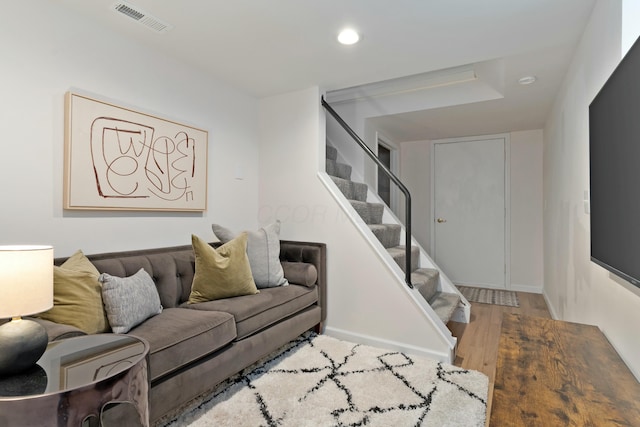 living area with visible vents, stairway, baseboards, and wood finished floors