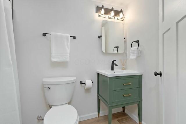 bathroom featuring vanity, wood finished floors, toilet, and baseboards