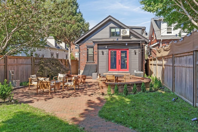 rear view of house with a patio area, french doors, a fenced backyard, and brick siding