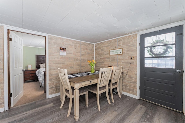 dining area featuring dark hardwood / wood-style flooring and brick wall