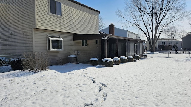 view of snow covered exterior featuring cooling unit and a sunroom