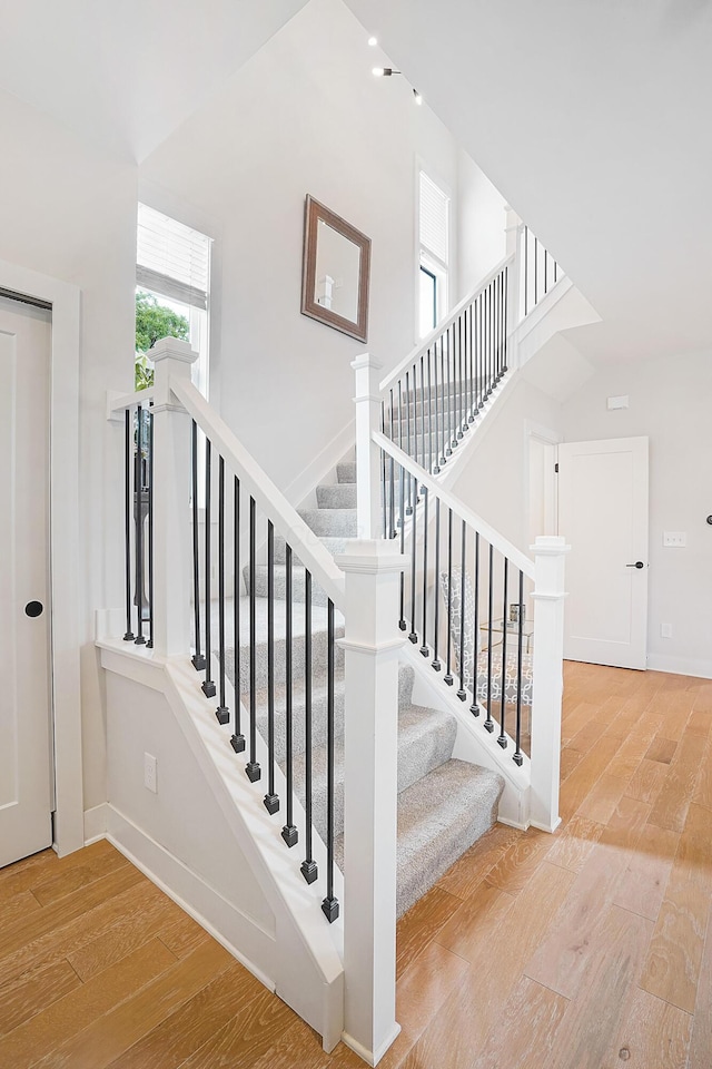 staircase with a high ceiling and hardwood / wood-style floors