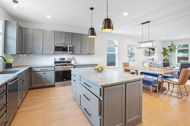 kitchen with sink, a center island, appliances with stainless steel finishes, gray cabinets, and pendant lighting