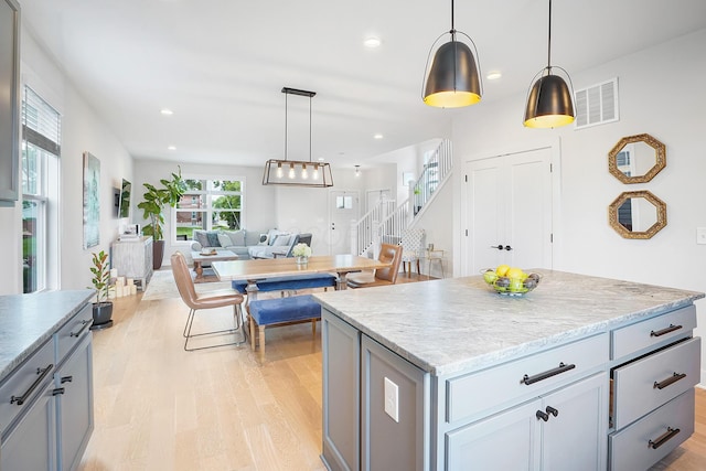 kitchen featuring gray cabinetry, hanging light fixtures, light hardwood / wood-style flooring, and a kitchen island