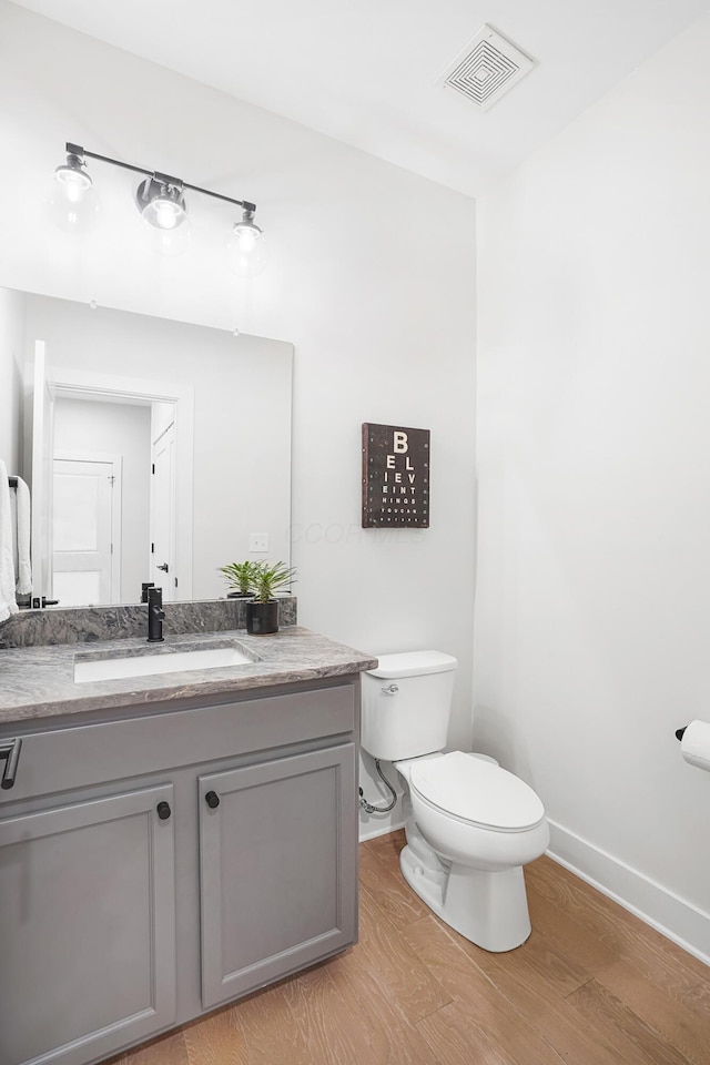 bathroom with hardwood / wood-style flooring, vanity, and toilet