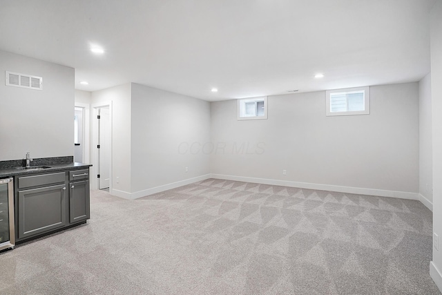 basement with light carpet, beverage cooler, and indoor wet bar