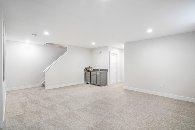 basement with wine cooler, light colored carpet, and wet bar