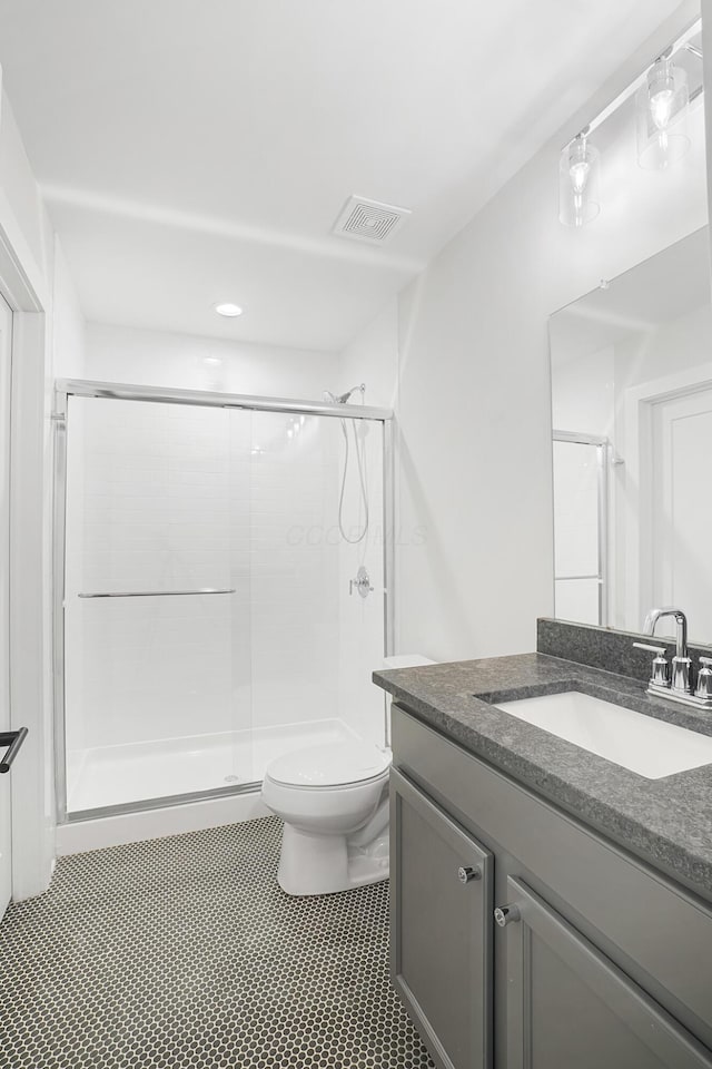 bathroom featuring vanity, a shower with shower door, and toilet