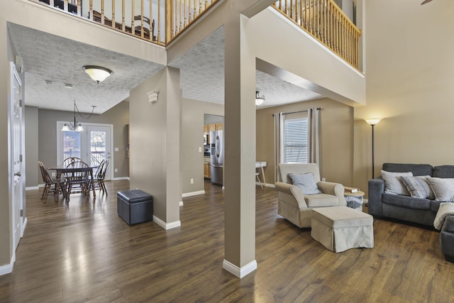 living room with a towering ceiling, baseboards, and dark wood finished floors