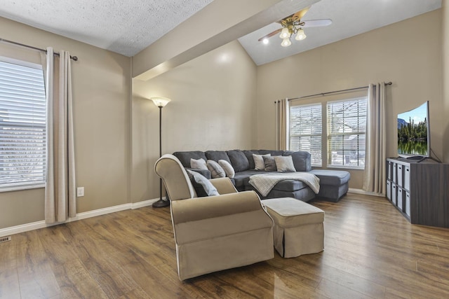 living area with a textured ceiling, baseboards, and wood finished floors