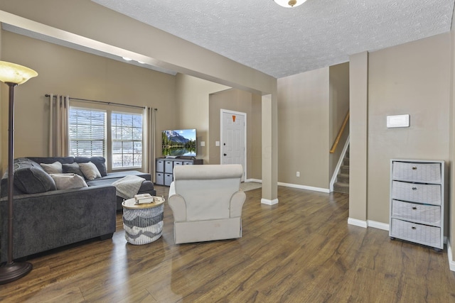 living room with dark wood-style floors, stairway, a textured ceiling, and baseboards