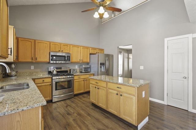 kitchen with light stone counters, a kitchen island, a sink, appliances with stainless steel finishes, and dark wood-style floors