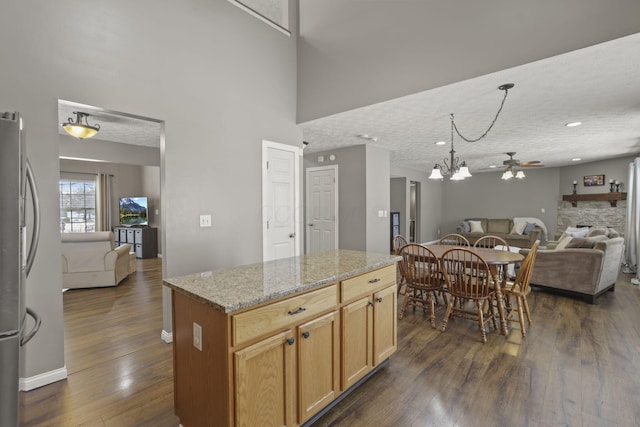 kitchen with dark wood finished floors, freestanding refrigerator, open floor plan, and a kitchen island