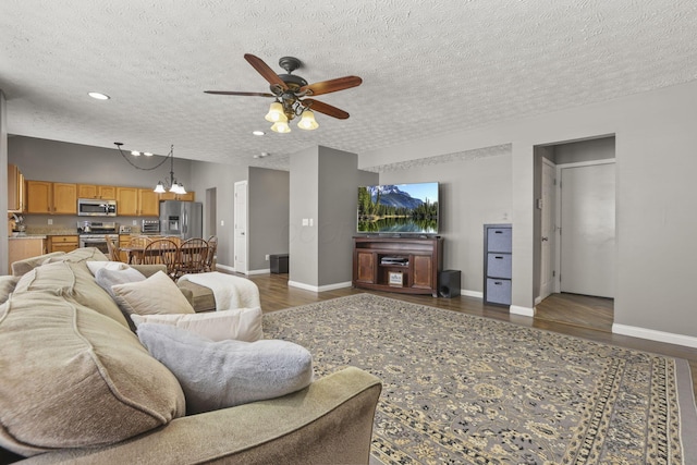 living area featuring dark wood-style floors, ceiling fan, a textured ceiling, and baseboards