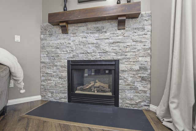 interior details featuring baseboards, wood finished floors, and a stone fireplace