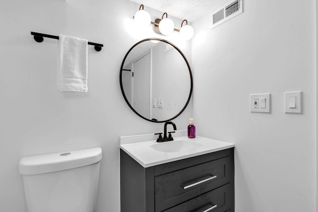 bathroom featuring a textured ceiling, toilet, and vanity