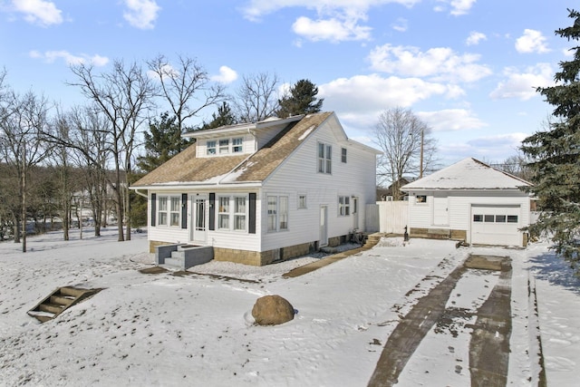 snow covered back of property with a garage and an outbuilding