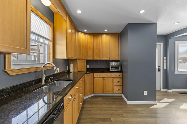 kitchen featuring sink, dark wood-type flooring, dark stone counters, and a healthy amount of sunlight