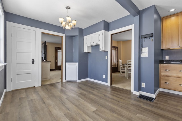 kitchen with decorative light fixtures, a chandelier, wood-type flooring, and white cabinets