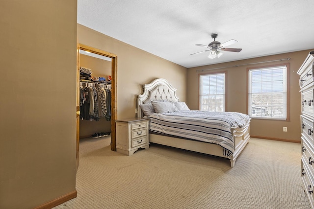 bedroom featuring a closet, a spacious closet, a textured ceiling, ceiling fan, and light carpet