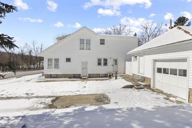 snow covered back of property featuring a garage