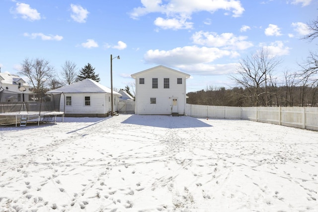 snow covered rear of property with a trampoline