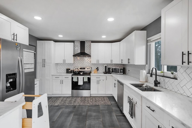 kitchen featuring wall chimney exhaust hood, appliances with stainless steel finishes, white cabinets, and a sink