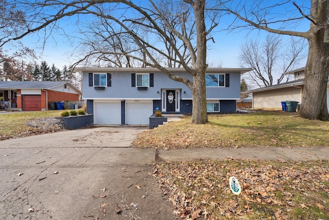 raised ranch with driveway, stucco siding, an attached garage, and a front yard