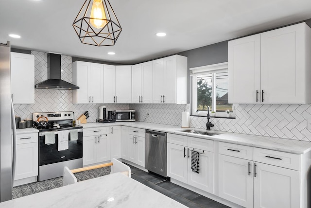 kitchen featuring stainless steel appliances, backsplash, white cabinets, a sink, and wall chimney exhaust hood