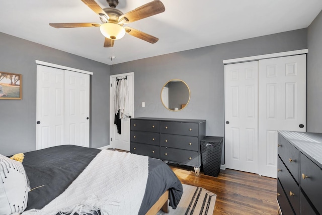 bedroom with dark wood-type flooring, two closets, and a ceiling fan