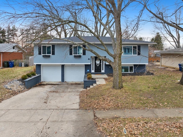 bi-level home with driveway, an attached garage, and stucco siding