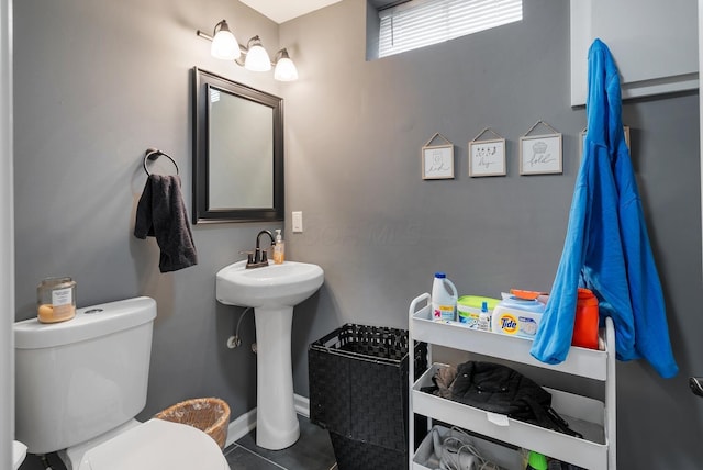 bathroom with toilet, baseboards, a sink, and tile patterned floors