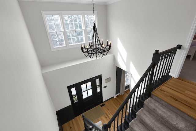 entrance foyer featuring an inviting chandelier, stairs, baseboards, and wood finished floors