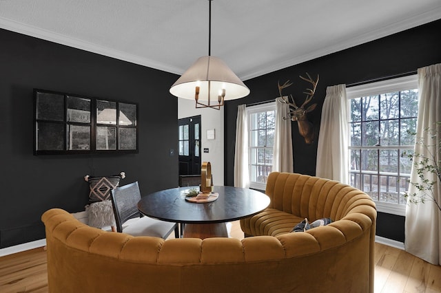 dining room with light wood finished floors, baseboards, and crown molding