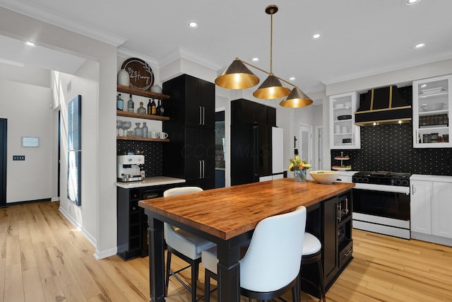 kitchen featuring high quality fridge, dark cabinets, butcher block countertops, open shelves, and gas range gas stove