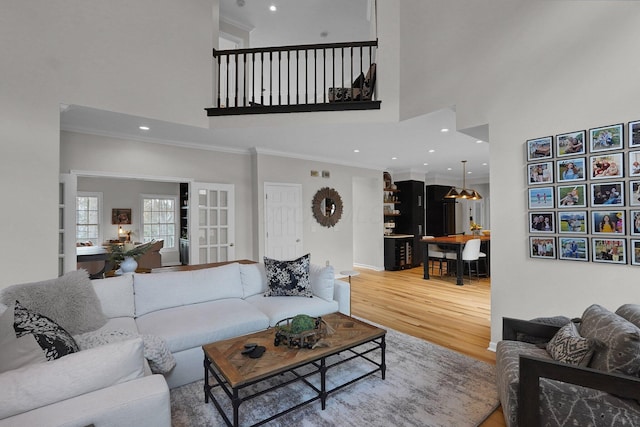 living room with a high ceiling, recessed lighting, wood finished floors, and crown molding