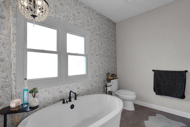 full bath featuring a freestanding bath, baseboards, an inviting chandelier, and wallpapered walls