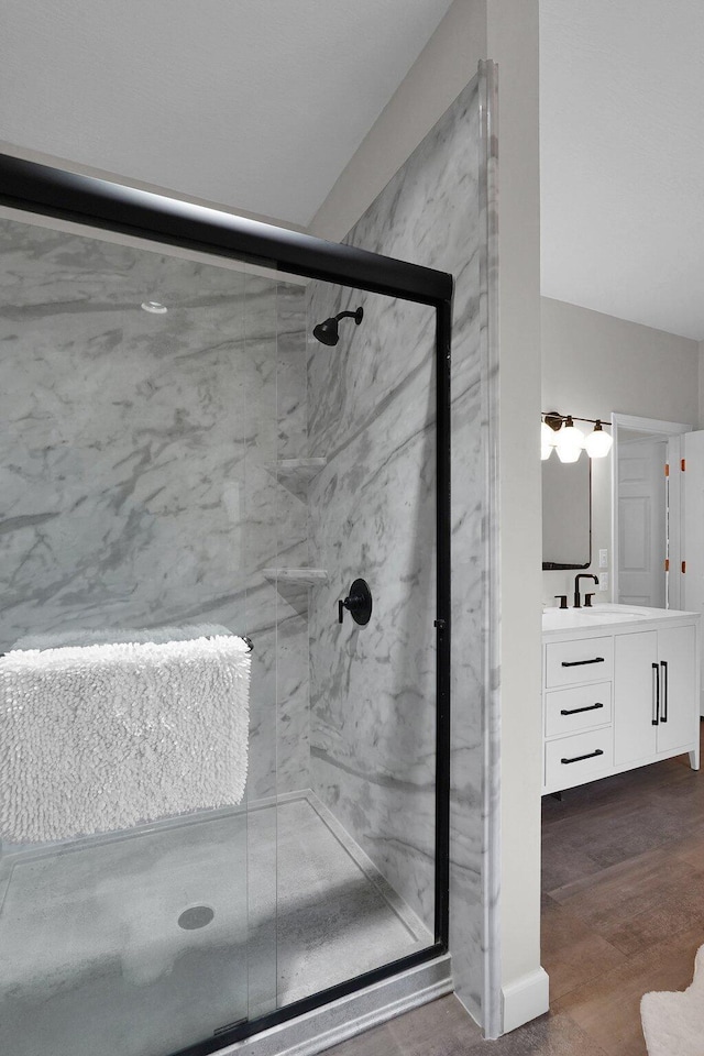 full bath with vanity, a marble finish shower, and wood finished floors