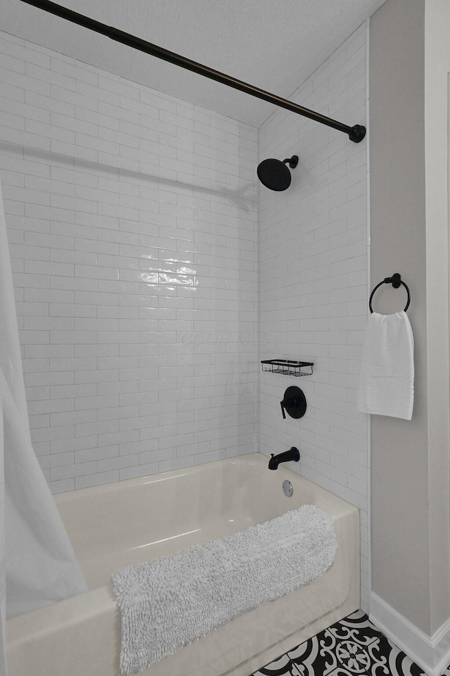 bathroom with shower / bathtub combination with curtain, baseboards, and a textured ceiling