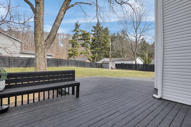 deck with a storage unit, a lawn, an outdoor structure, and a fenced backyard