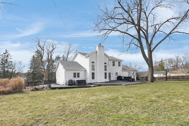 rear view of property with a chimney, fence, a deck, and a lawn