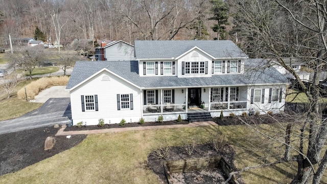 view of front of house featuring driveway, a front lawn, a porch, and roof with shingles