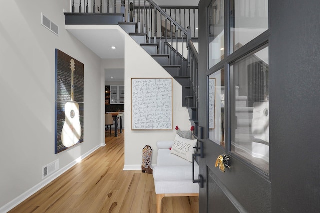 entrance foyer featuring stairway, a high ceiling, visible vents, and wood finished floors