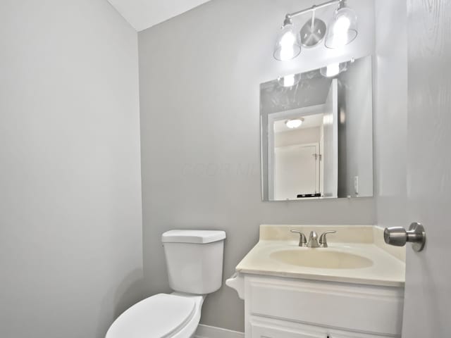 bathroom featuring toilet, baseboards, and vanity