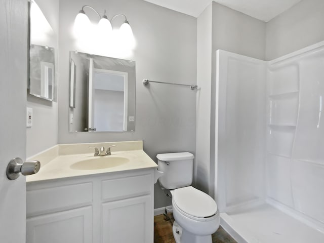 full bath with a stall shower, baseboards, vanity, and toilet