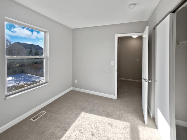 unfurnished bedroom featuring light carpet, a closet, visible vents, and baseboards