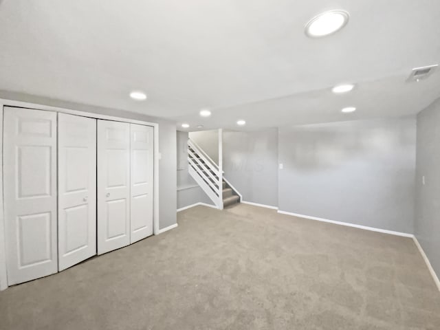 finished below grade area featuring recessed lighting, light colored carpet, visible vents, stairway, and baseboards