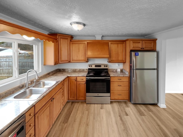 kitchen featuring sink, light wood-type flooring, a textured ceiling, stainless steel appliances, and ornamental molding