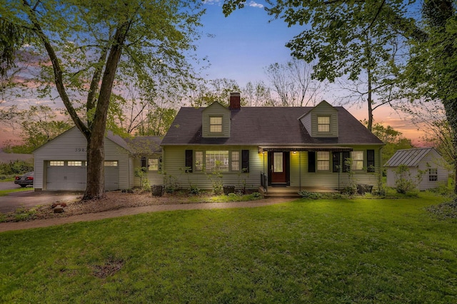 new england style home with driveway, a chimney, and a front lawn